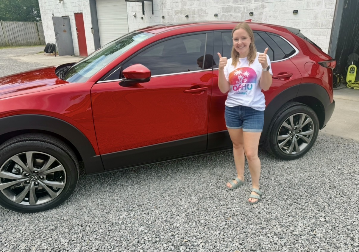 Happy Lavigne Autospa customer with freshly detailed red SUV